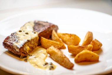 Kızarmış patates dilimleri ve biftek ve biber sosu.