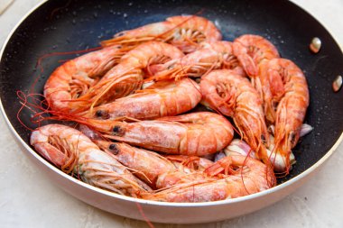 Bir tavada sarımsak ile tavada kızartılmış büyük portakal karides.