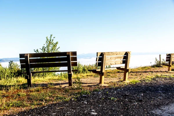 Wooden benches on top of a mountain overlooking the valley. Morn