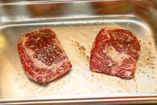 Råa ribeye steak beströs med salt och peppar och smord befo — Stockfoto