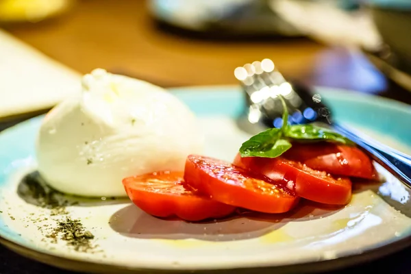 Domates dilimleri ve burrata peynir plaka üzerinde vardır. sürüm o