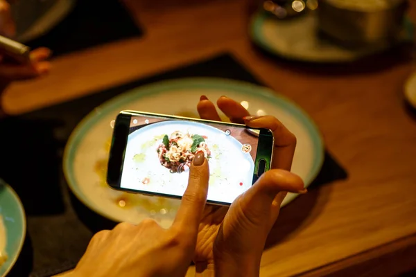 Dziewczyna w restauracji fotografować jedzenie na telefon. — Zdjęcie stockowe