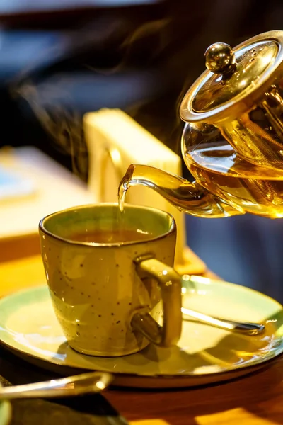 Heißer Tee wird aus der gläsernen Teekanne in die Tasse gegossen — Stockfoto