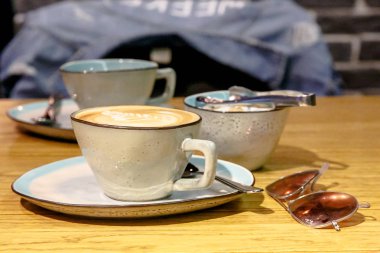 Fincan cappuccino bir desen ile ve kahverengi şeker kaseyle ve