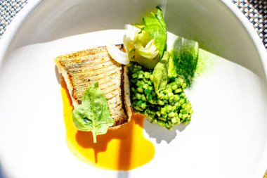 Izgara balık COD beyaz bir plaka üzerinde yatıyor.