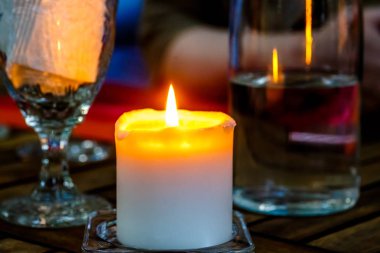 Şarap, gözlük ve yanan bir muma akşam masada. 