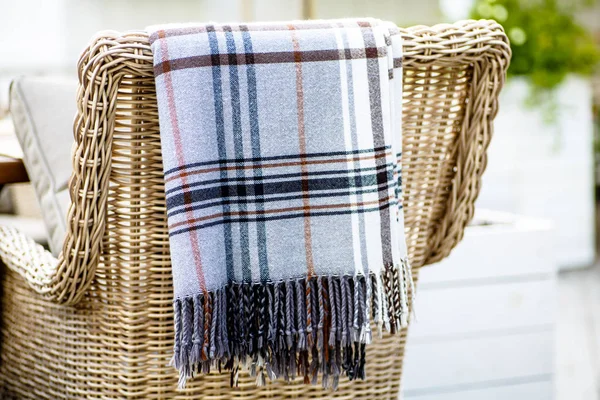 Plaid lies on the wicker furniture from rattan. Summer.