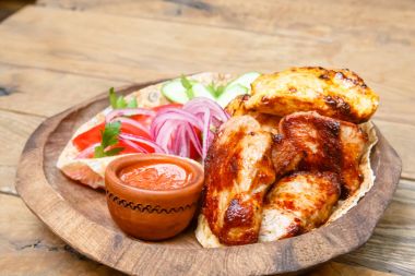 Kırmızı soğan ve peynir bir ahşap plaka üzerinde yalan tavuk kebabı.