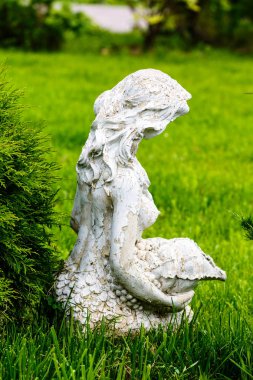 Eski çim bir parkta oturan bir kız heykeli.