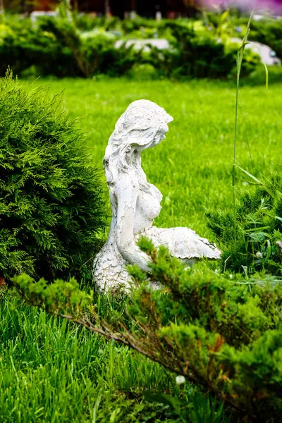 Antigua estatua de una chica sentada en un parque en la hierba . — Foto de Stock