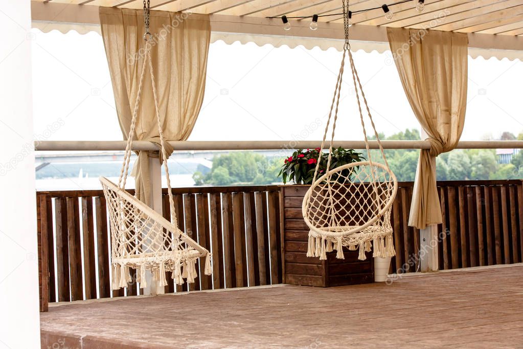 Round swinging chair in the gazebo outdoors. Summer