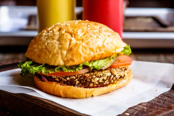 Un burger régulier avec une côtelette repose sur du papier — Photo