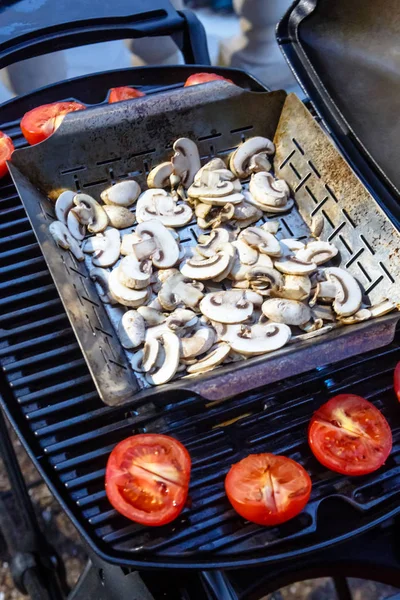 Tomates e cogumelos são fritos na grelha a churrasqueira a gás . — Fotografia de Stock