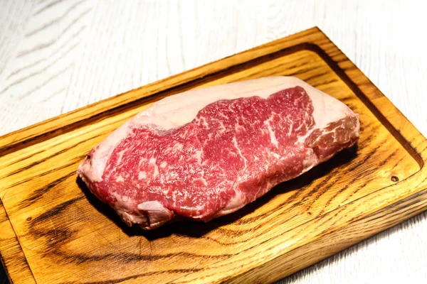Rohes Ribeye Steak auf dem Brett liegend. — Stockfoto
