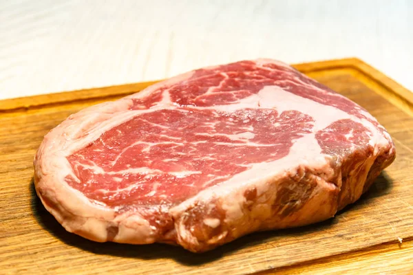 Råa ribeye steak liggande på styrelsen. — Stockfoto