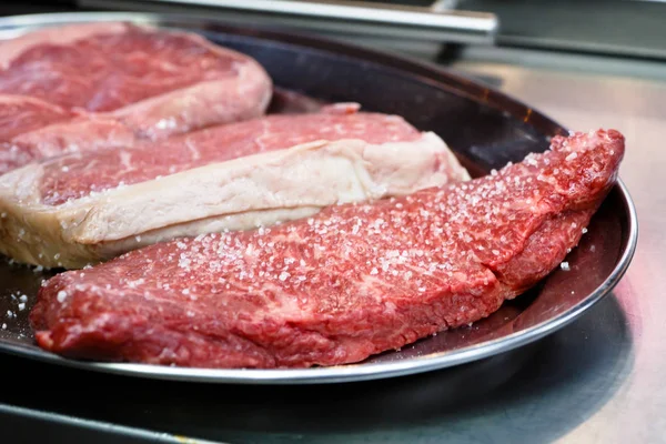 Kocken tillagar biffar till stekning - salt och olja med vegetabilisk oi — Stockfoto