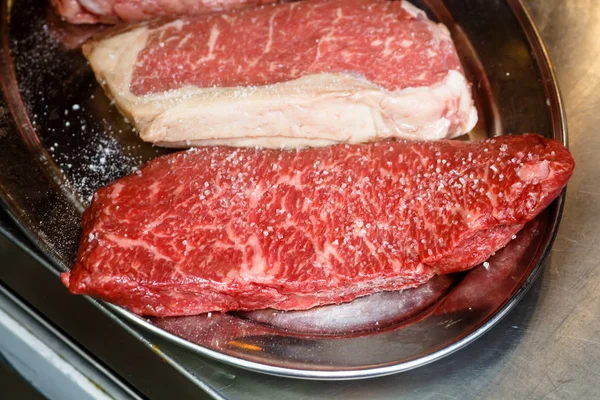 Chef prépare des steaks pour la friture - sel et huile avec oi végétal — Photo