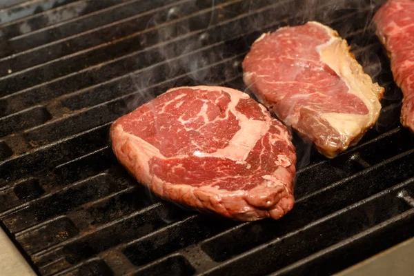 Der Koch kocht Steaks auf dem Grill. — Stockfoto