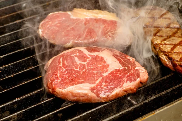 Šéfkuchař vaří steaky na grilu. — Stock fotografie