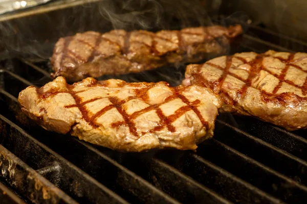 Der Koch kocht Steaks auf dem Grill. — Stockfoto