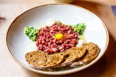 Sığır eti çiğ yumurta, salatalık ve ekmek dilimleri.