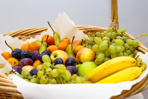 Cesta de frutas de vime: uvas, ameixas, bananas, maçãs, damascos, p — Fotografia de Stock