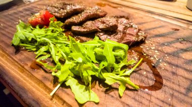 Dilimlenmiş kuzu kızartma ve roka ile bir gemide yalan.