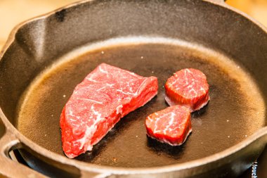 Bir tavada birkaç mermer sığır eti dilim kızarmış.