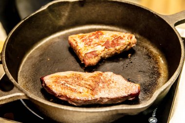 Bir tavada birkaç mermer sığır eti dilim kızarmış.