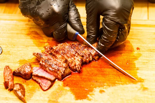 The chef cuts beef steak roasting rare.