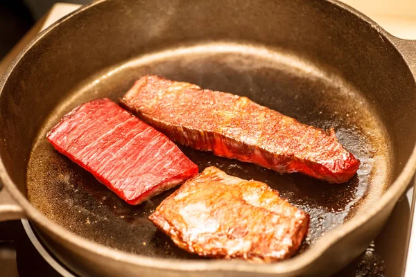 Mehrere Scheiben marmoriertes Rindfleisch werden in einer Pfanne gebraten. — Stockfoto