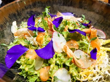 Taze çiçeklerle süslenmiş sebze salatası