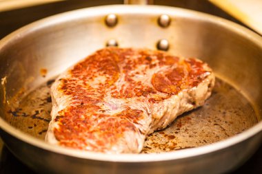 Üzerinde çelik bir tavada kızarmış rampa biftek.