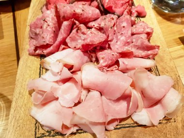 Salam ve sosis dilimleri bir ahşap tahta üzerinde yalan.