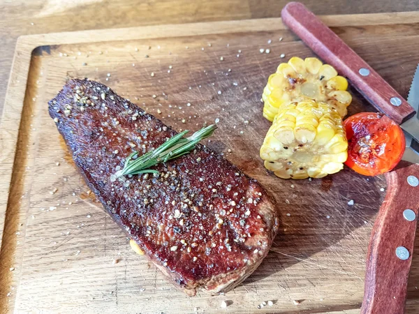 Beef steak sprinkled with pepper and salt lies on a Board with c — Stock Photo, Image