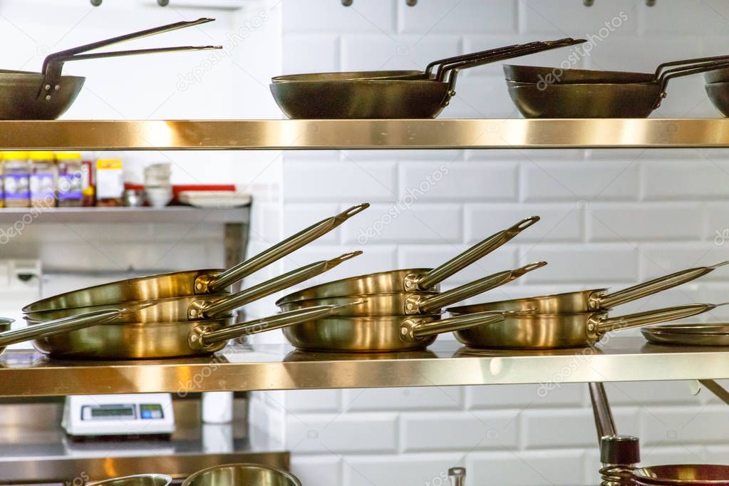 Restaurant kitchen. Pans are on the shelf.