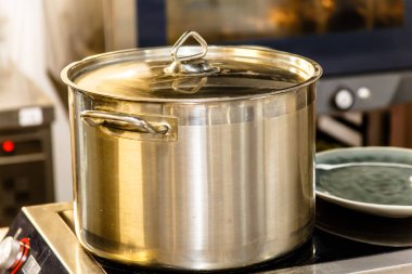 Suyu yemek pişirmek için bir çelik tencereye ocakta standları.