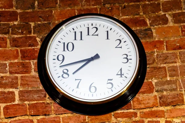 Στρογγυλό ρολόι που κρέμεται στον τοίχο κόκκινο τούβλο. — Φωτογραφία Αρχείου
