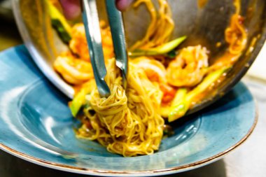 Cook makarna sebze ve karides ile bir pla koyar.