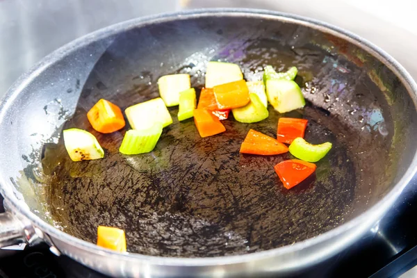 Sweet peppers and celery are fried in a pan. — Stock Photo, Image