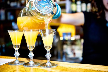 Barmen yüksek bacağa sarı kokteyller döker.