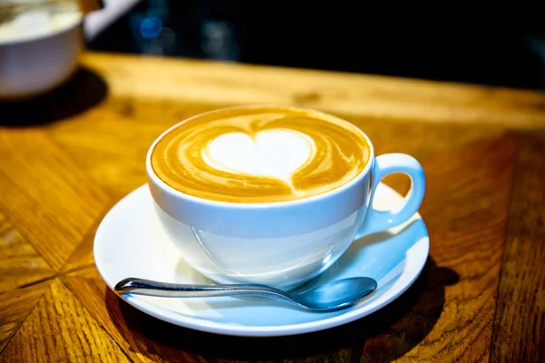 Szív a cappuccino kupán egy fa asztalon — Stock Fotó