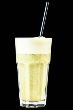 Bitki ve sebzelerden yapılmış yeşil smoothie büyük bir bardakta siyah taş bir duvara karşı.