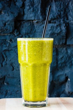 Sarı smoothie (portakal, mandarin) büyük cam bir fincanda siyah bir duvara karşı.