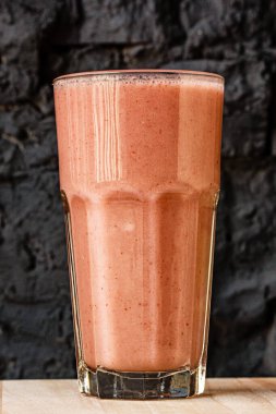 Büyük cam bir bardakta siyah bir duvara yaslanmış turuncu narenciye.