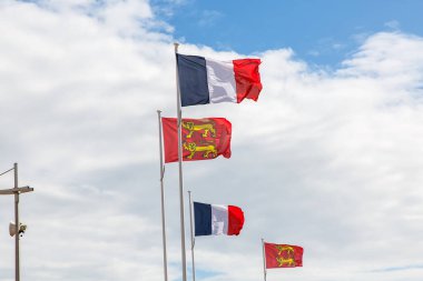 Bulutlu mavi gökyüzüne karşı Fransa ve Normandiya bayrağı.