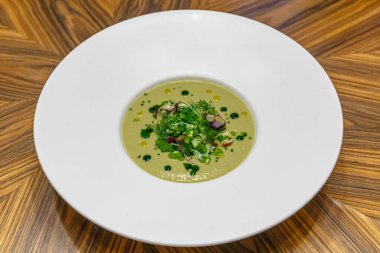 Salatalık ve yeşilliklerden gelen soğuk krema çorbası beyaz bir tabağa dökülür.