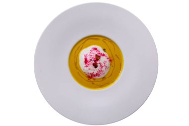 Ekşi kremalı balkabağı kremalı çorba ve beyaz tabakta pancar tozu ile süslenmiş..