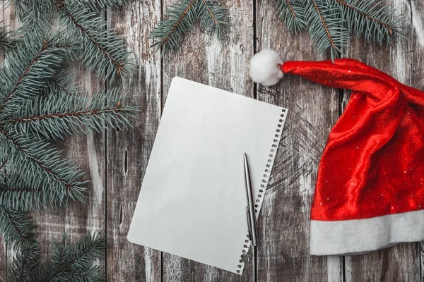 Eski ahşap arka plan üzerinde Noel Baba'nın şapka ve yeşil çam dalları ile neşeli Noel mektubu. — Stok fotoğraf
