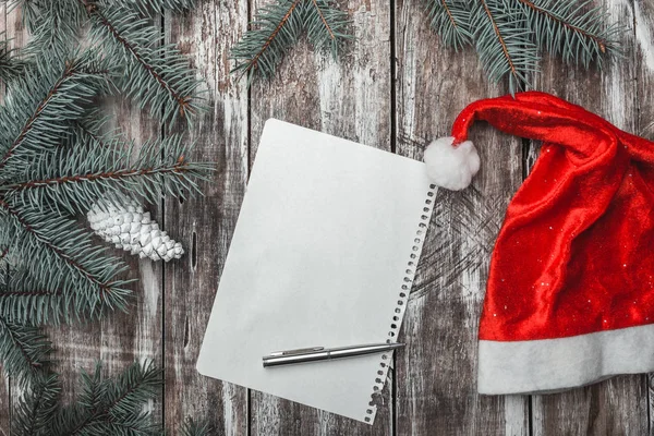 Eski ahşap arka plan üzerinde Noel Baba'nın şapka ve yeşil çam dalları ile neşeli Noel mektubu. — Stok fotoğraf